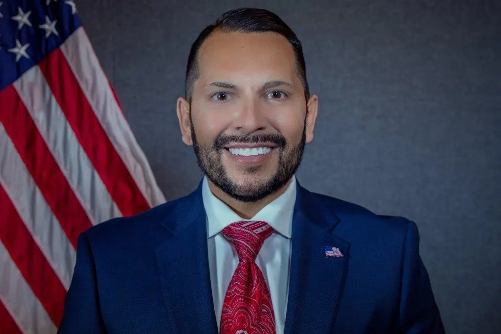 Man smiling with American flag background.