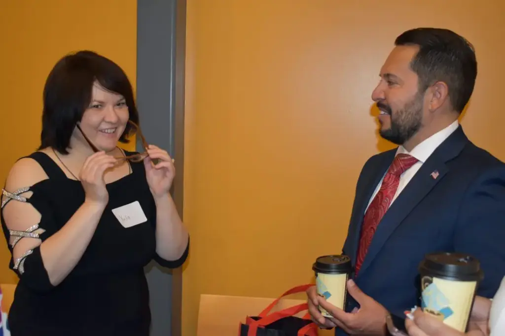 Two people talking, holding coffee cups.