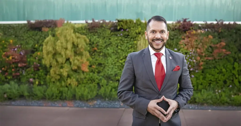 Smiling man in suit with green background.