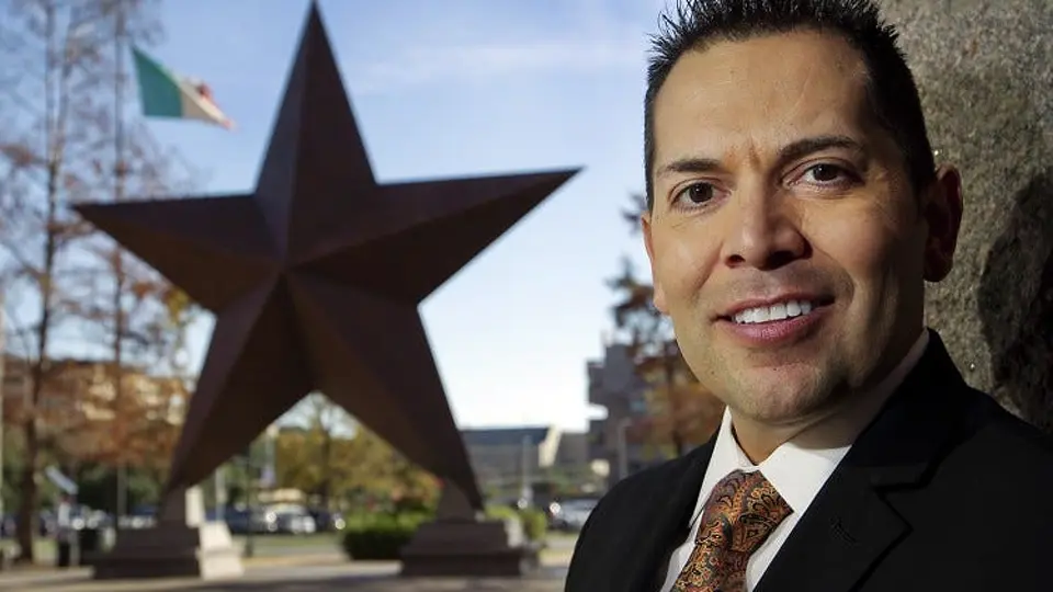 Man smiling near large star sculpture outdoors.
